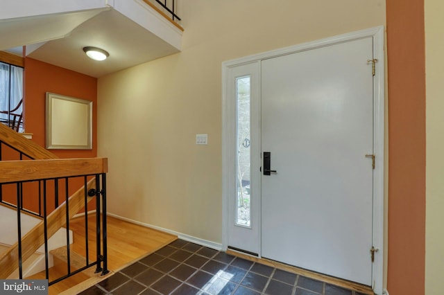 foyer with baseboards, dark wood-style floors, and stairs