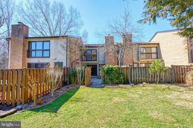 rear view of property with a lawn, a fenced backyard, and a chimney