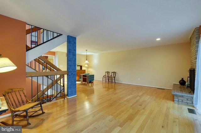 living area featuring stairs, visible vents, wood finished floors, and a fireplace