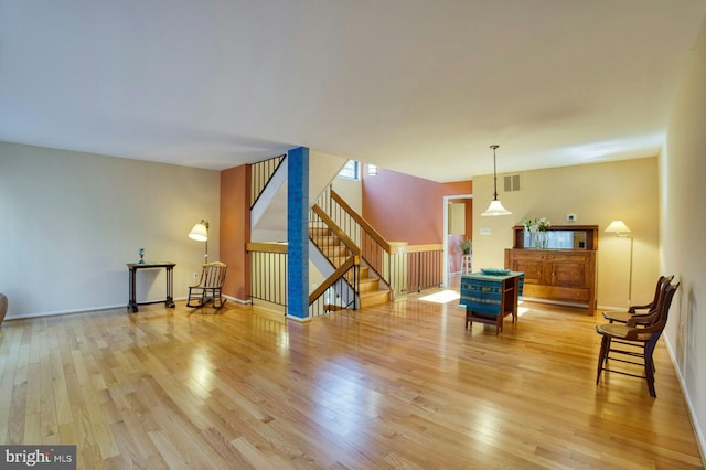 sitting room with stairs, wood finished floors, visible vents, and baseboards