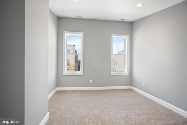 empty room with baseboards, light colored carpet, and a healthy amount of sunlight