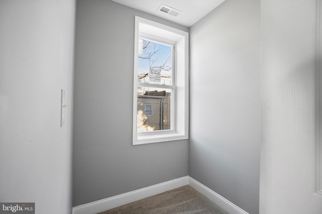 carpeted empty room featuring visible vents and baseboards