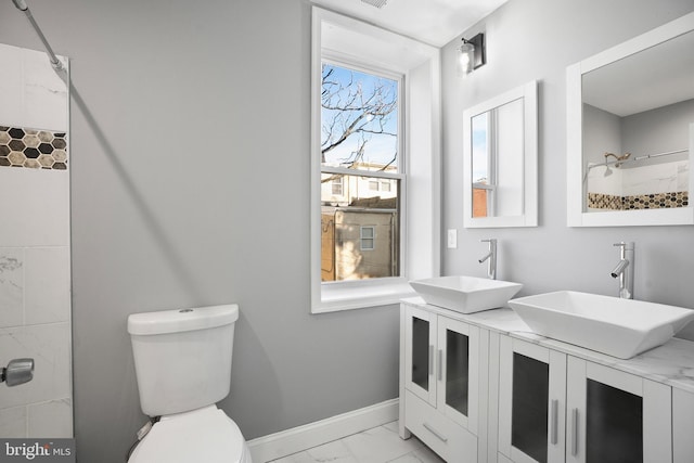 full bathroom featuring marble finish floor, double vanity, a sink, and baseboards