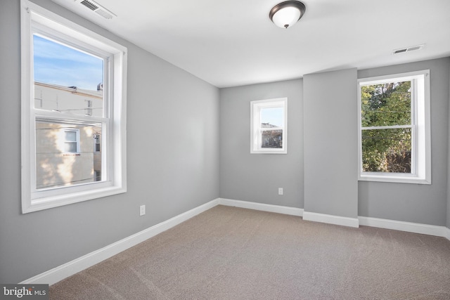 unfurnished room featuring carpet, visible vents, and baseboards