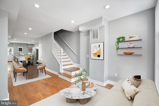 living area featuring stairs, light wood-style flooring, and recessed lighting