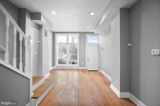 foyer entrance with recessed lighting, baseboards, light wood finished floors, and stairs