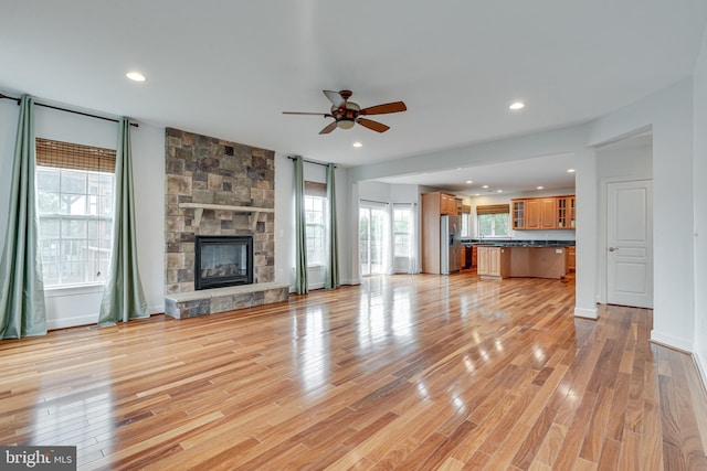 16309 Sandy Ridge Ct, Woodbridge, VA 22191 - unfurnished living room with a ceiling fan, light wood-style flooring, recessed lighting, a stone fireplace, and baseboards