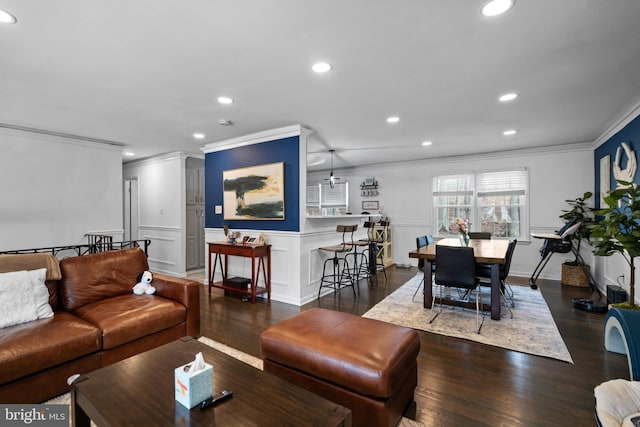 living area with a wainscoted wall, dark wood finished floors, crown molding, and recessed lighting