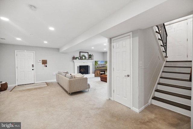 living area featuring recessed lighting, light colored carpet, stairway, a brick fireplace, and baseboards