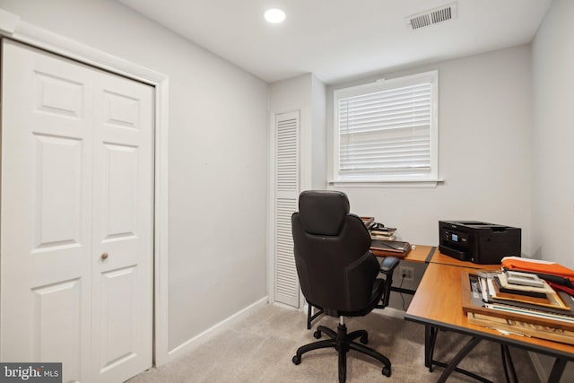 office featuring visible vents, light carpet, and baseboards