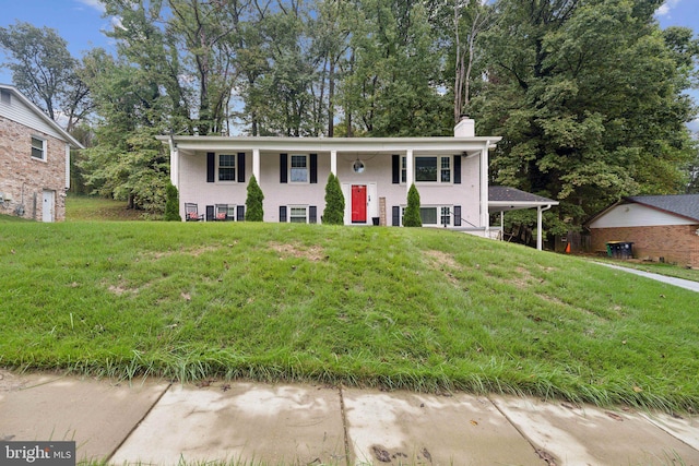 split foyer home with a chimney and a front lawn