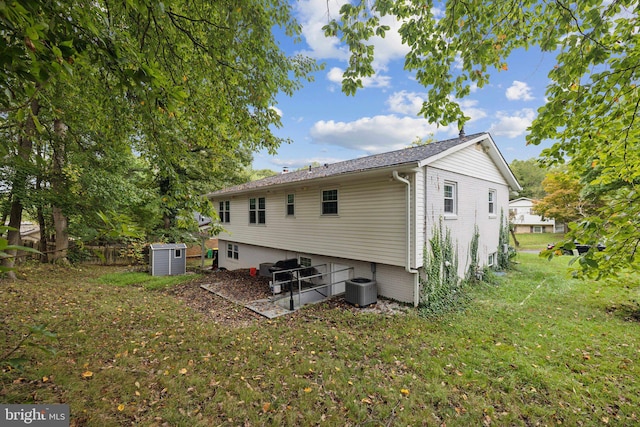 rear view of property featuring brick siding, a lawn, fence, and central air condition unit