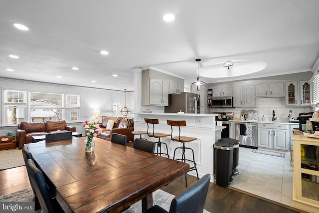 dining area featuring ornamental molding, light wood-style flooring, and recessed lighting