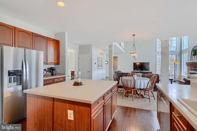 kitchen with dark wood-type flooring, decorative light fixtures, open floor plan, light countertops, and appliances with stainless steel finishes