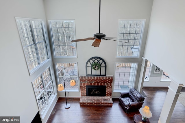 living room with plenty of natural light, a high ceiling, a ceiling fan, and wood finished floors