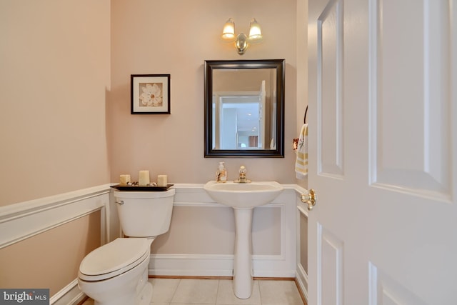 half bathroom featuring tile patterned flooring, toilet, and baseboards