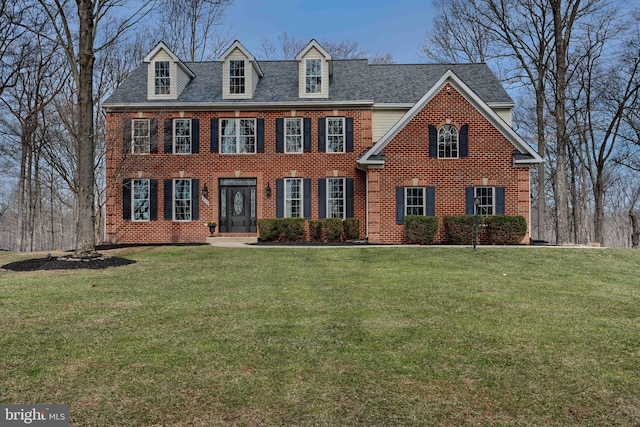 view of front of property featuring a front yard, brick siding, and roof with shingles