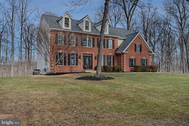 colonial home with brick siding, central air condition unit, a front lawn, and roof with shingles