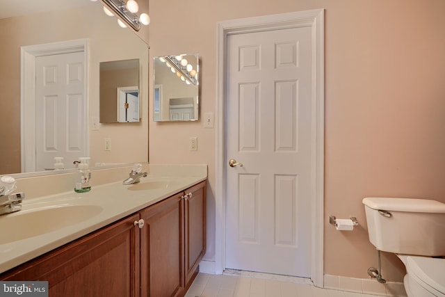 bathroom with a sink, toilet, double vanity, and tile patterned floors