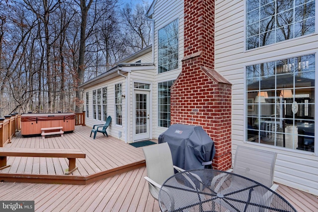 wooden terrace featuring outdoor dining area, area for grilling, and a hot tub