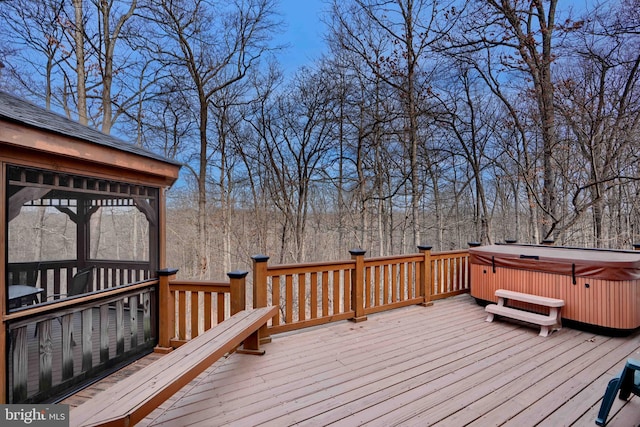 wooden terrace with a view of trees and a hot tub