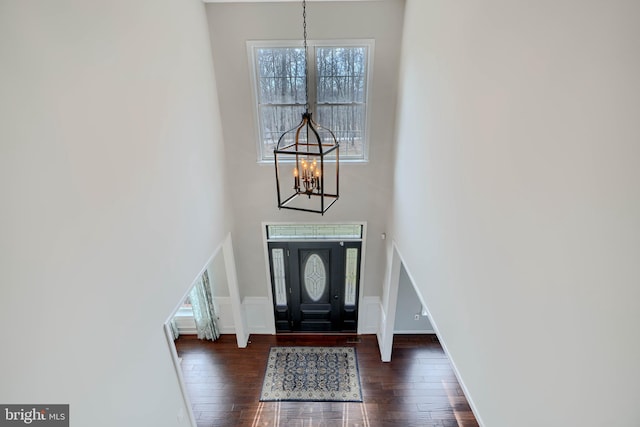 foyer entrance with baseboards, an inviting chandelier, a towering ceiling, and hardwood / wood-style flooring