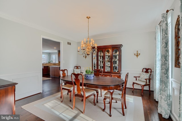 dining space featuring an inviting chandelier, ornamental molding, visible vents, and dark wood-type flooring