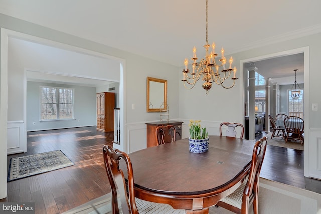 dining room featuring a wainscoted wall, dark wood finished floors, an inviting chandelier, ornamental molding, and a decorative wall