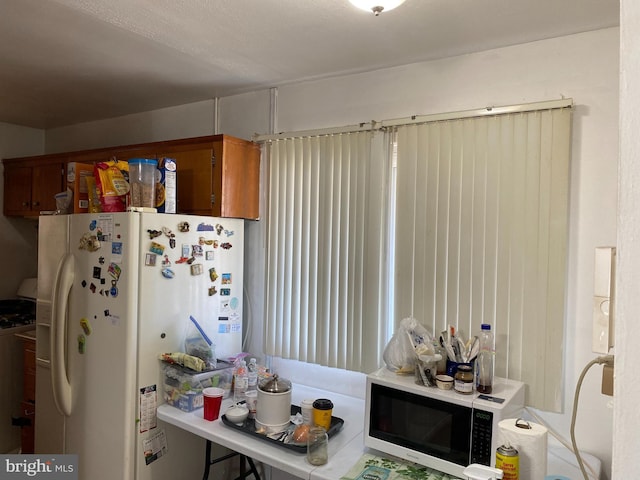 kitchen with range with gas cooktop, brown cabinets, and white fridge with ice dispenser