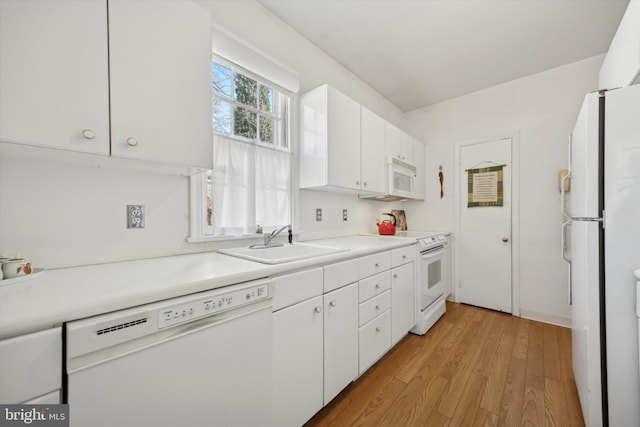 kitchen with light countertops, white cabinets, a sink, light wood-type flooring, and white appliances