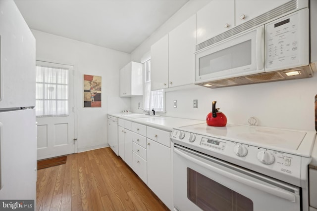 kitchen with white appliances, white cabinetry, light wood finished floors, and a healthy amount of sunlight