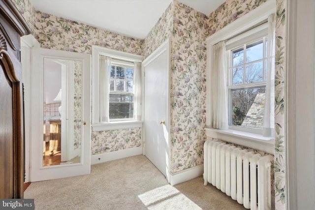 interior space with a healthy amount of sunlight, wallpapered walls, and radiator heating unit