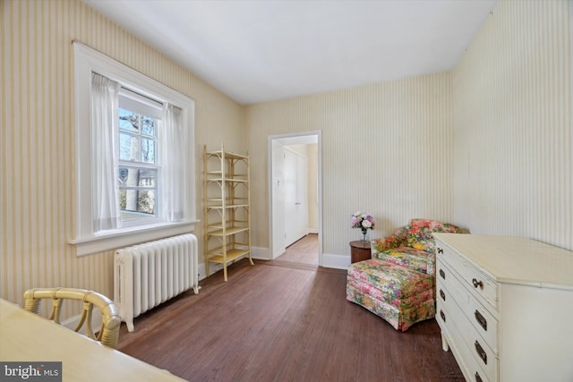 sitting room featuring radiator, wallpapered walls, baseboards, and wood finished floors