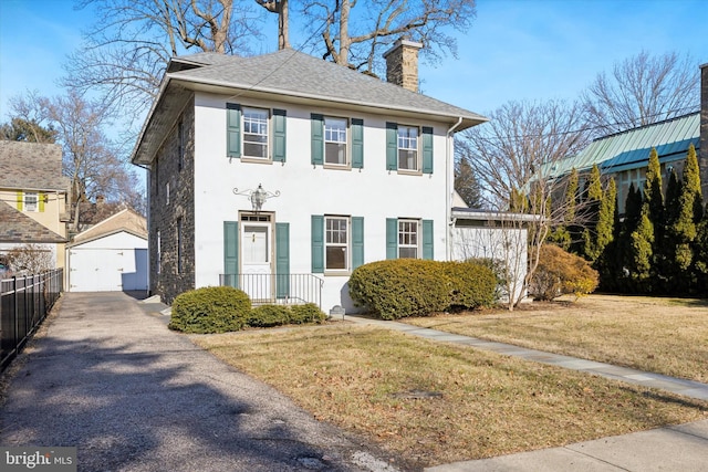 view of front facade with a chimney, fence, an outdoor structure, a front yard, and stucco siding