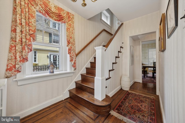 stairs with wallpapered walls, baseboards, and wood finished floors