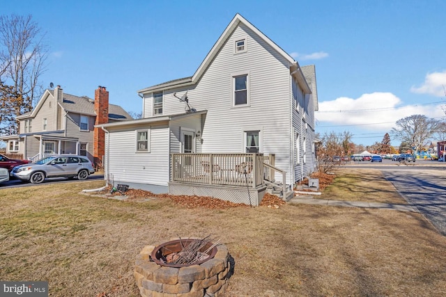 rear view of property with a yard and an outdoor fire pit