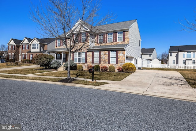 view of front facade featuring concrete driveway, an attached garage, fence, a residential view, and stone siding