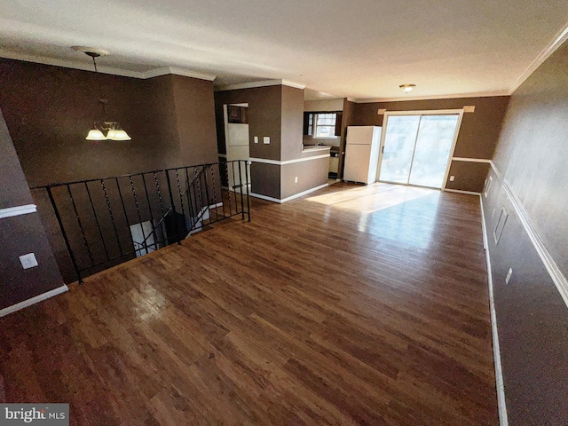 unfurnished living room with ornamental molding, wood finished floors, and baseboards