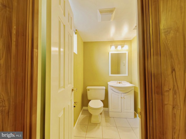 half bath with visible vents, toilet, vanity, tile patterned flooring, and baseboards