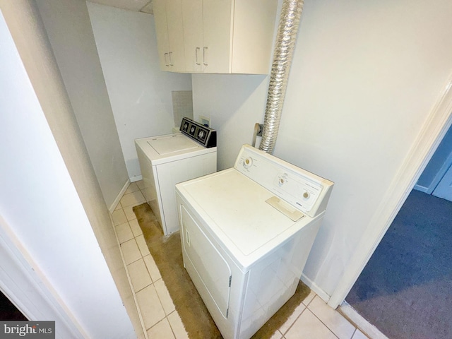 laundry room with light tile patterned floors, independent washer and dryer, cabinet space, and baseboards