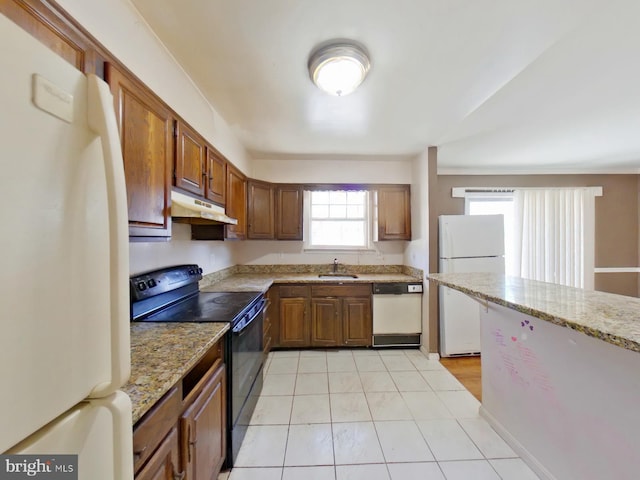 kitchen with white appliances, brown cabinets, and under cabinet range hood