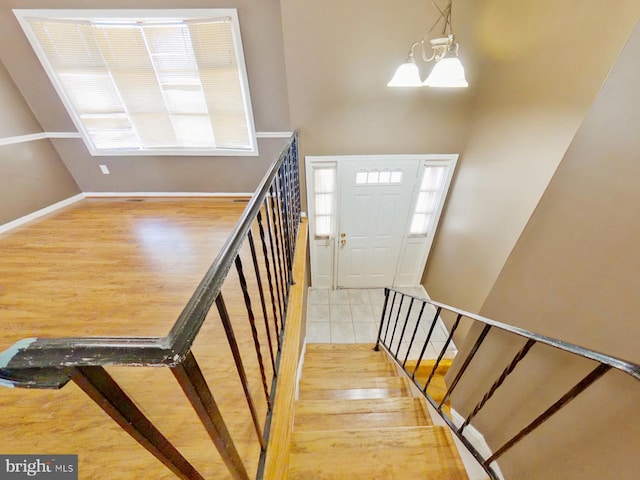 staircase with a chandelier, baseboards, and wood finished floors