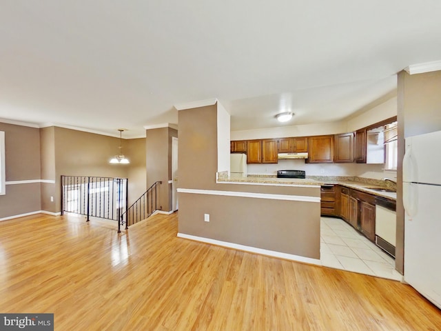 kitchen featuring white appliances, light countertops, light wood-type flooring, under cabinet range hood, and a sink