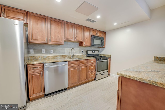 kitchen with visible vents, brown cabinets, a sink, stainless steel appliances, and backsplash