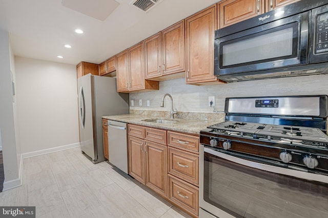 kitchen featuring a sink, visible vents, appliances with stainless steel finishes, backsplash, and light stone countertops