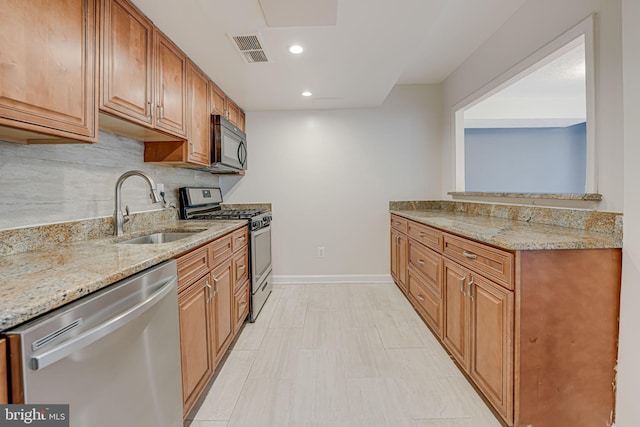 kitchen featuring visible vents, decorative backsplash, appliances with stainless steel finishes, light stone countertops, and a sink