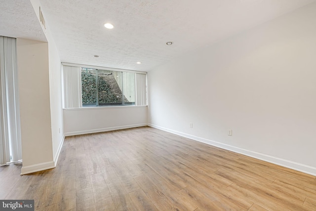 unfurnished room featuring recessed lighting, a textured ceiling, baseboards, and wood finished floors