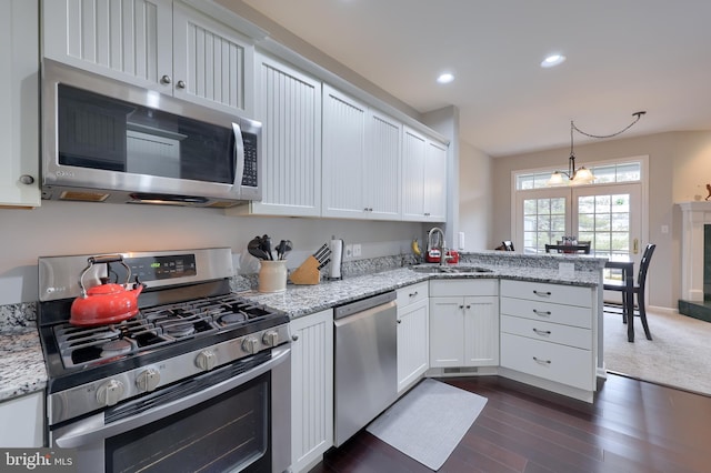 kitchen with recessed lighting, a peninsula, a sink, white cabinetry, and appliances with stainless steel finishes