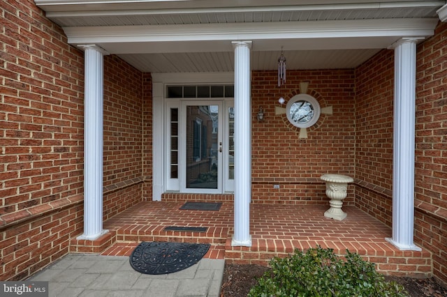 property entrance featuring a porch and brick siding