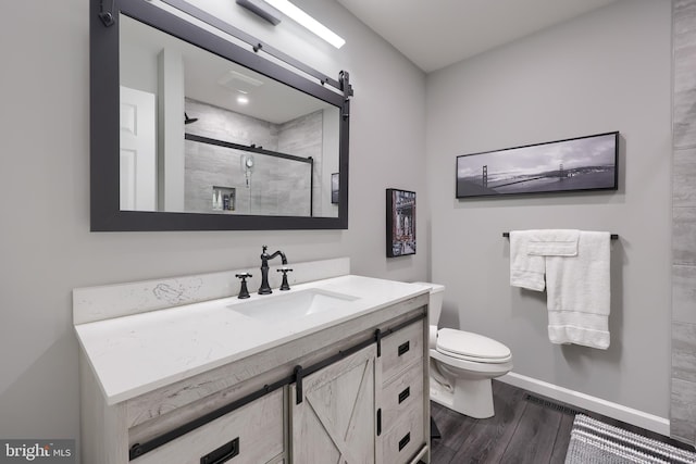 bathroom featuring toilet, wood finished floors, vanity, baseboards, and a shower stall